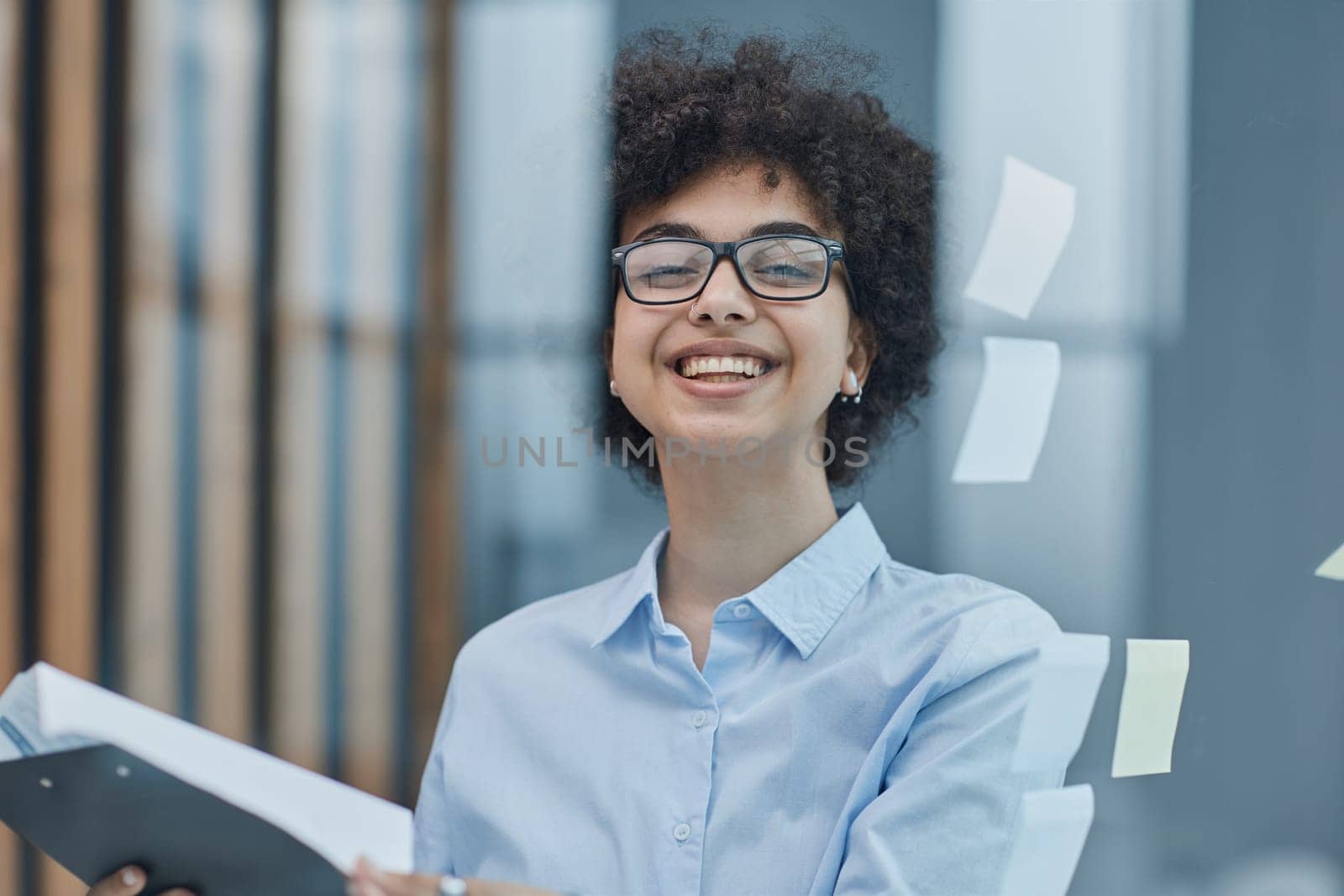 a girl in a modern office behind glass uses sticky notes and makes notes.