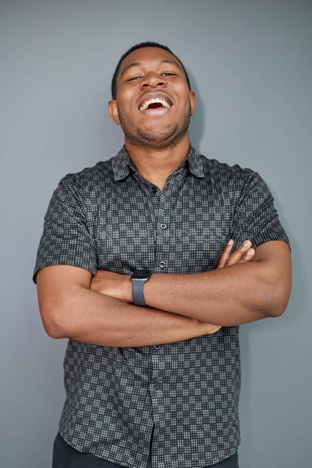 Portrait of a black man with his arms crossed on a gray background.