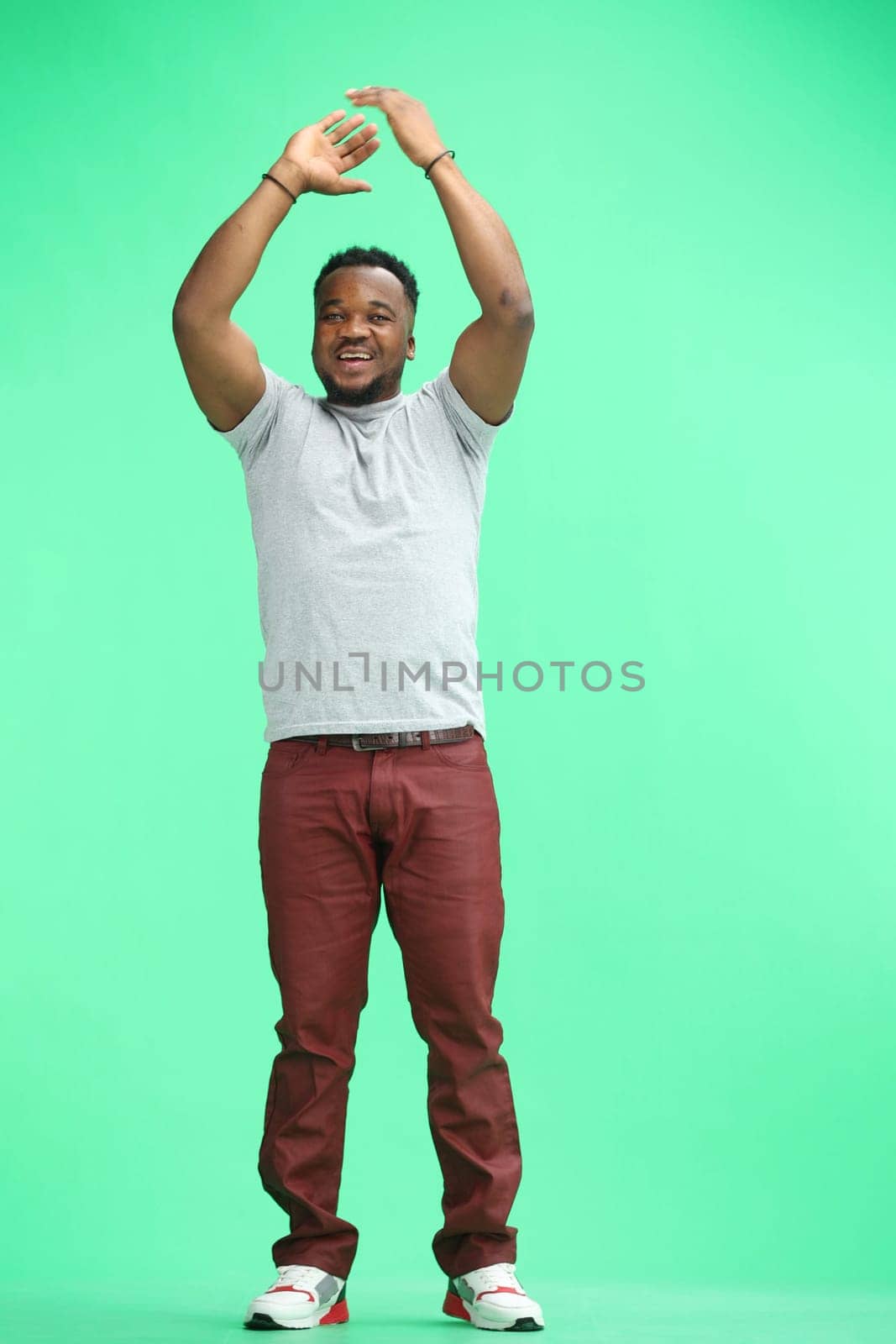 A man, full-length, on a green background, clapping.