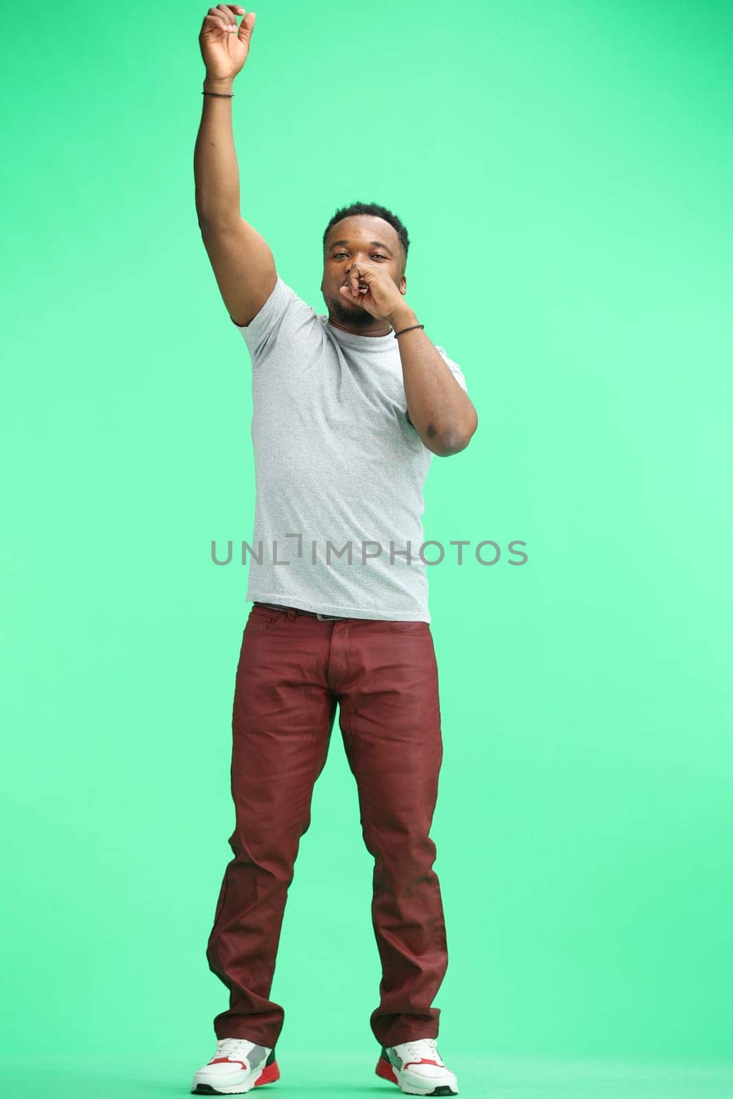 A man, full-length, on a green background, rejoicing.