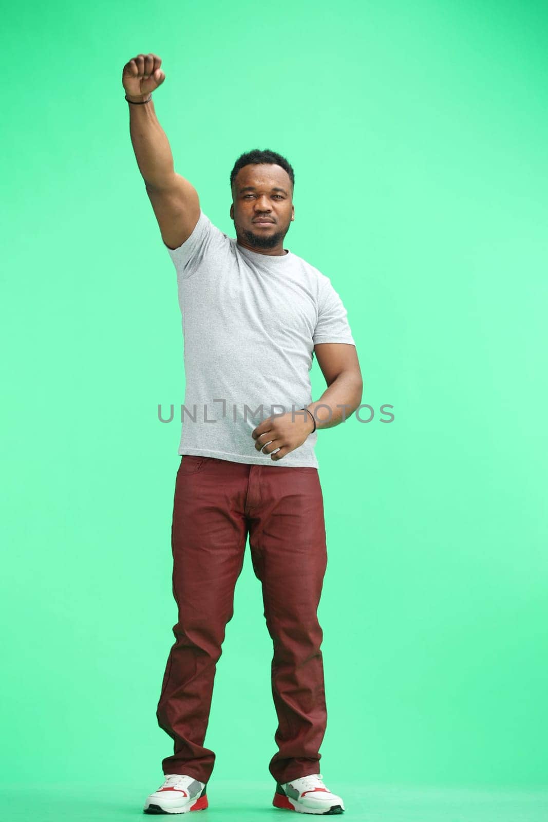 A man, full-length, on a green background, rejoicing.