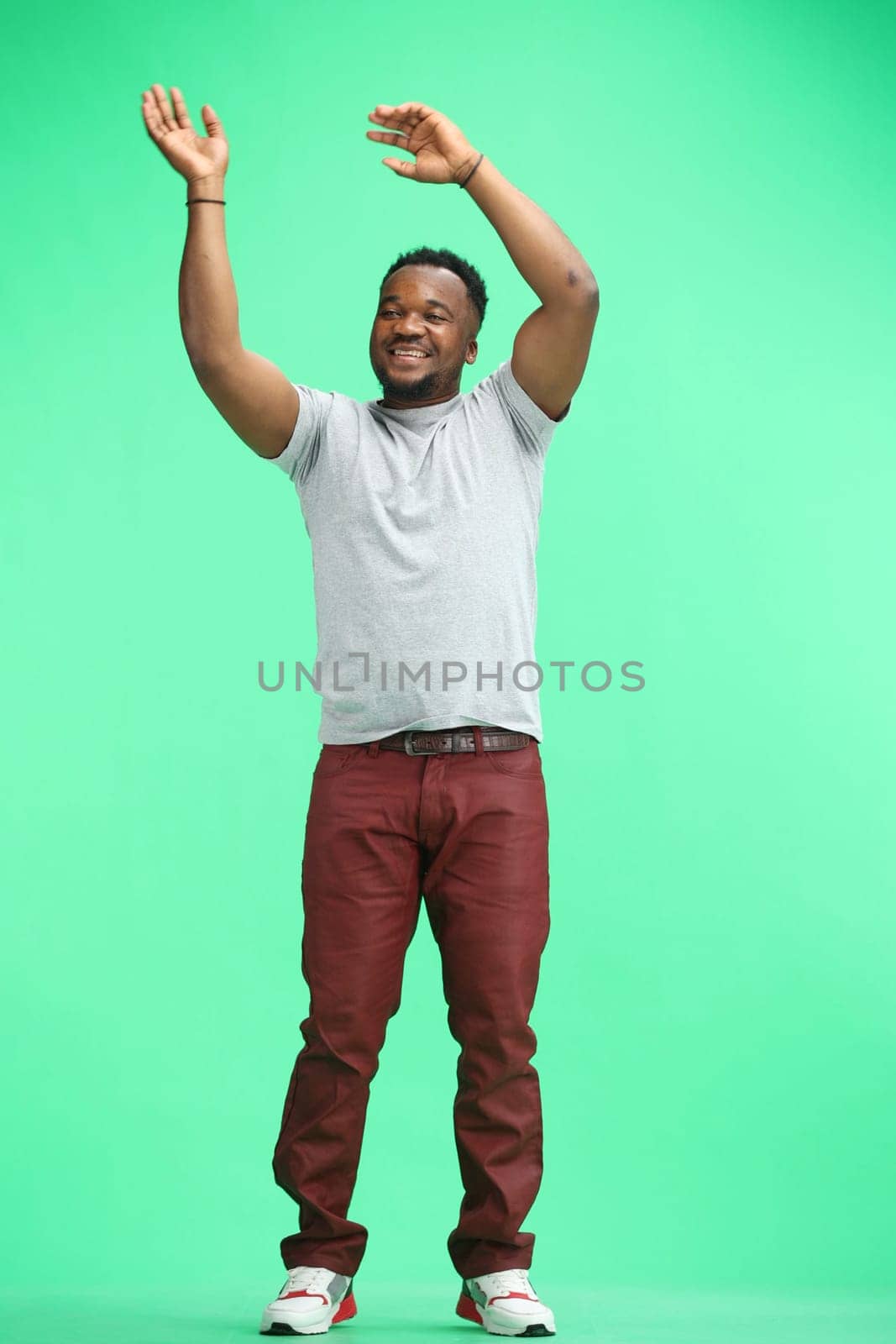 Man, full-length, on a green background, waving their hands.