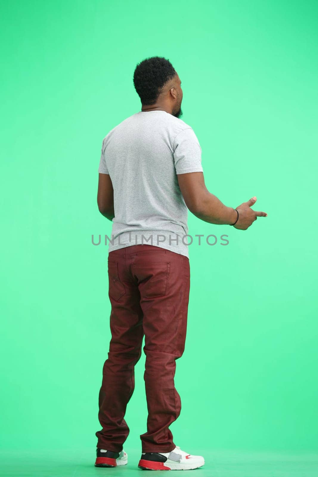 Man, full-length, on a green background, spreads their arms by Prosto