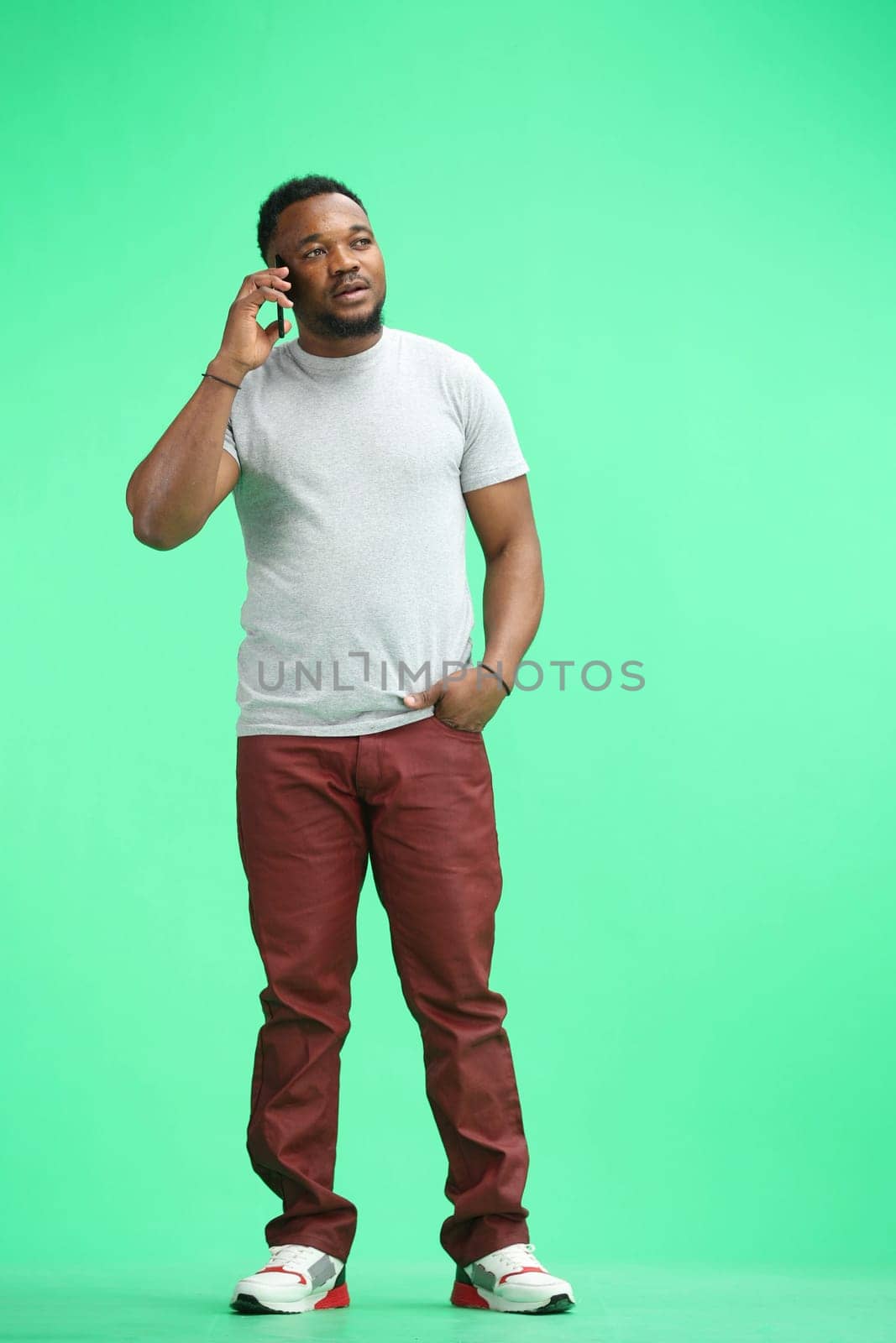 Man, full-length, on a green background, talking on the phone by Prosto