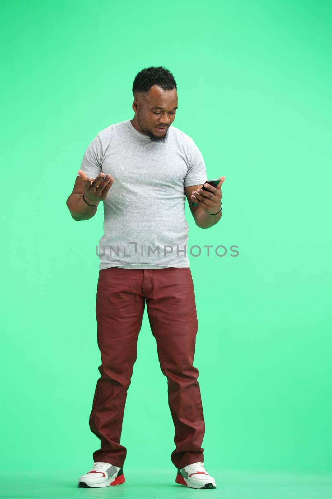 Man, full-length, on a green background, using a phone by Prosto