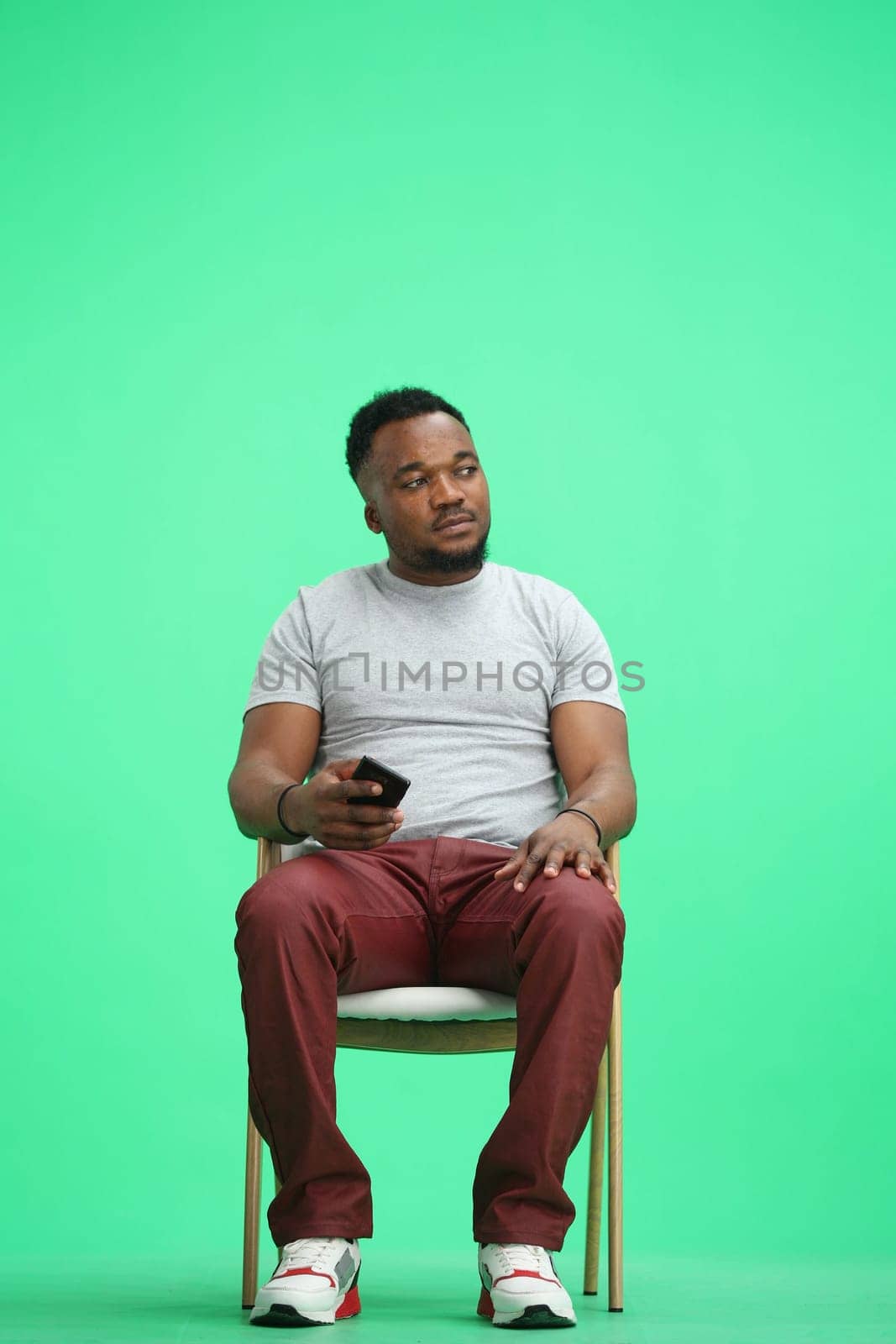 Man, on a green background, sitting on a chair by Prosto