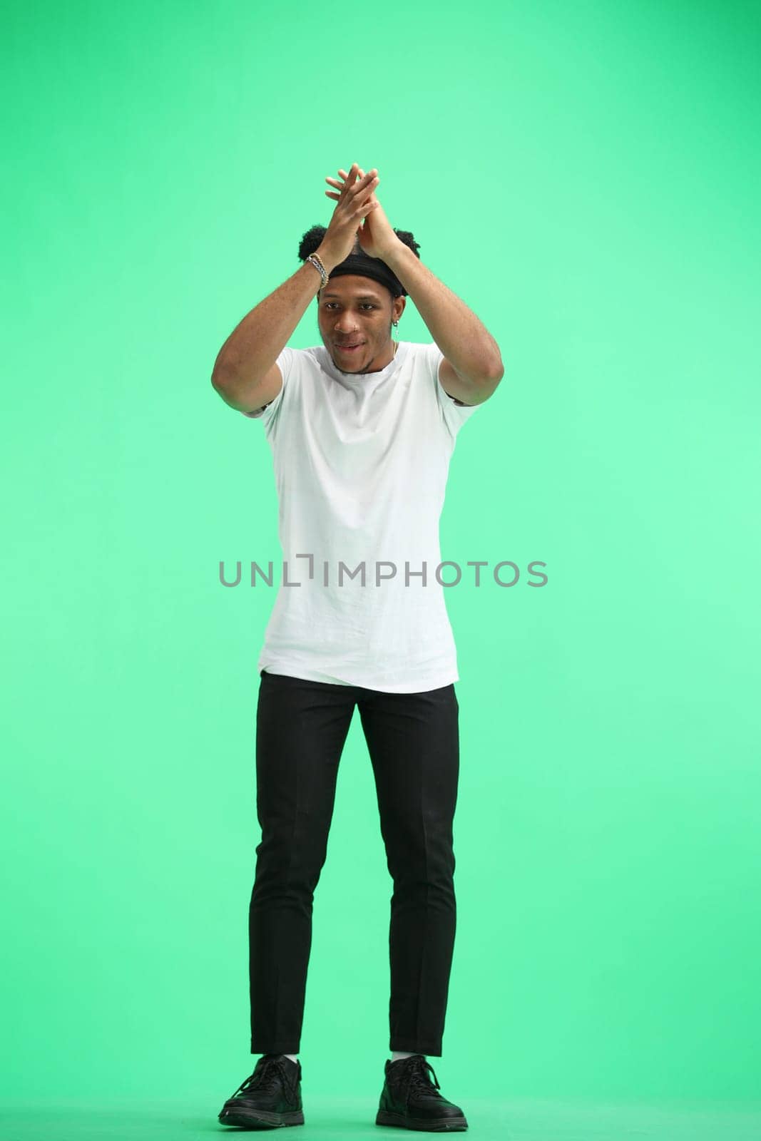 A man, full-length, on a green background, claps by Prosto