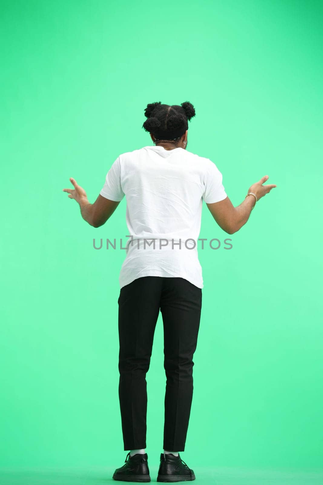 Man, full-length, on a green background, spreading their hands.