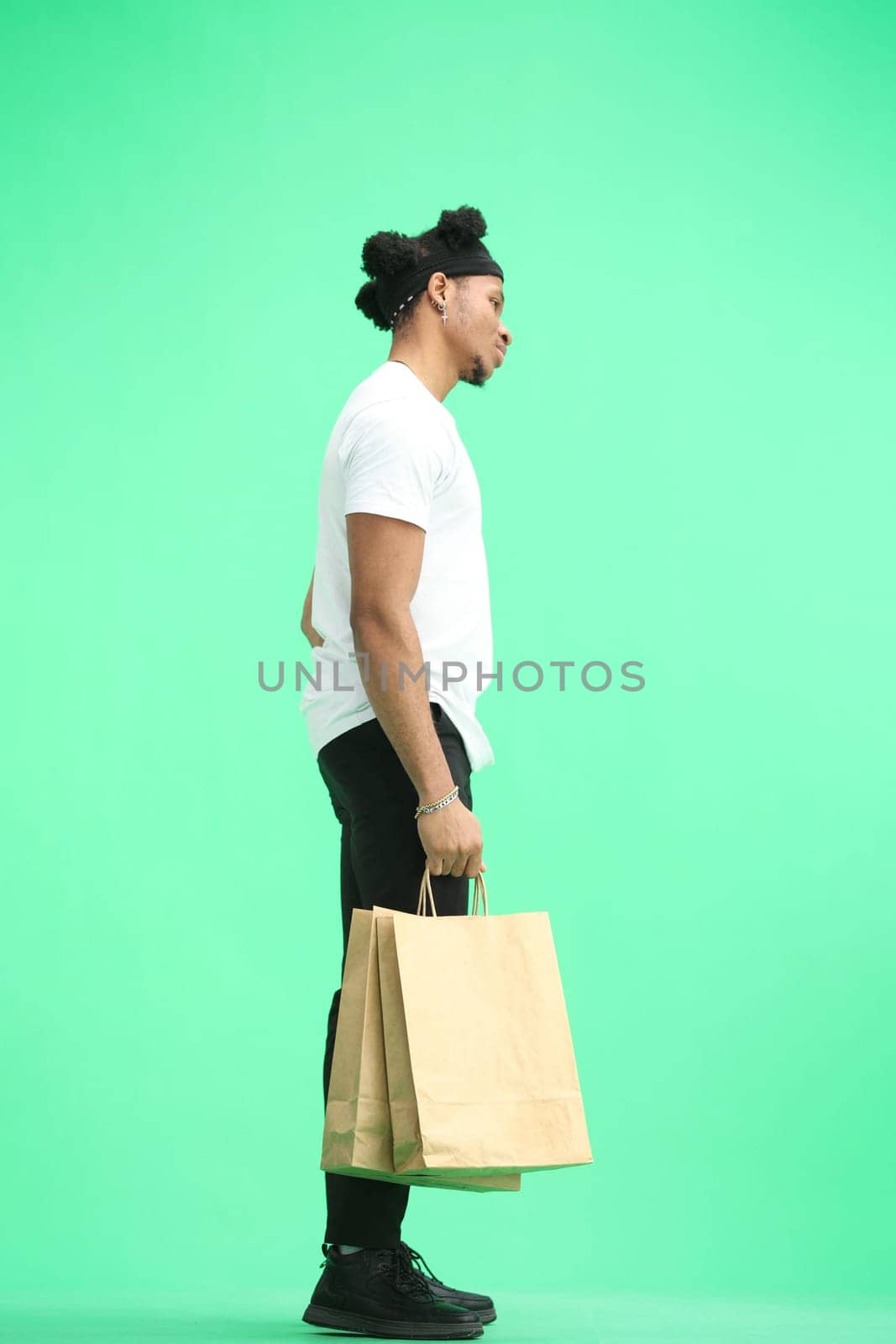 A man, full-length, on a green background, with bags.