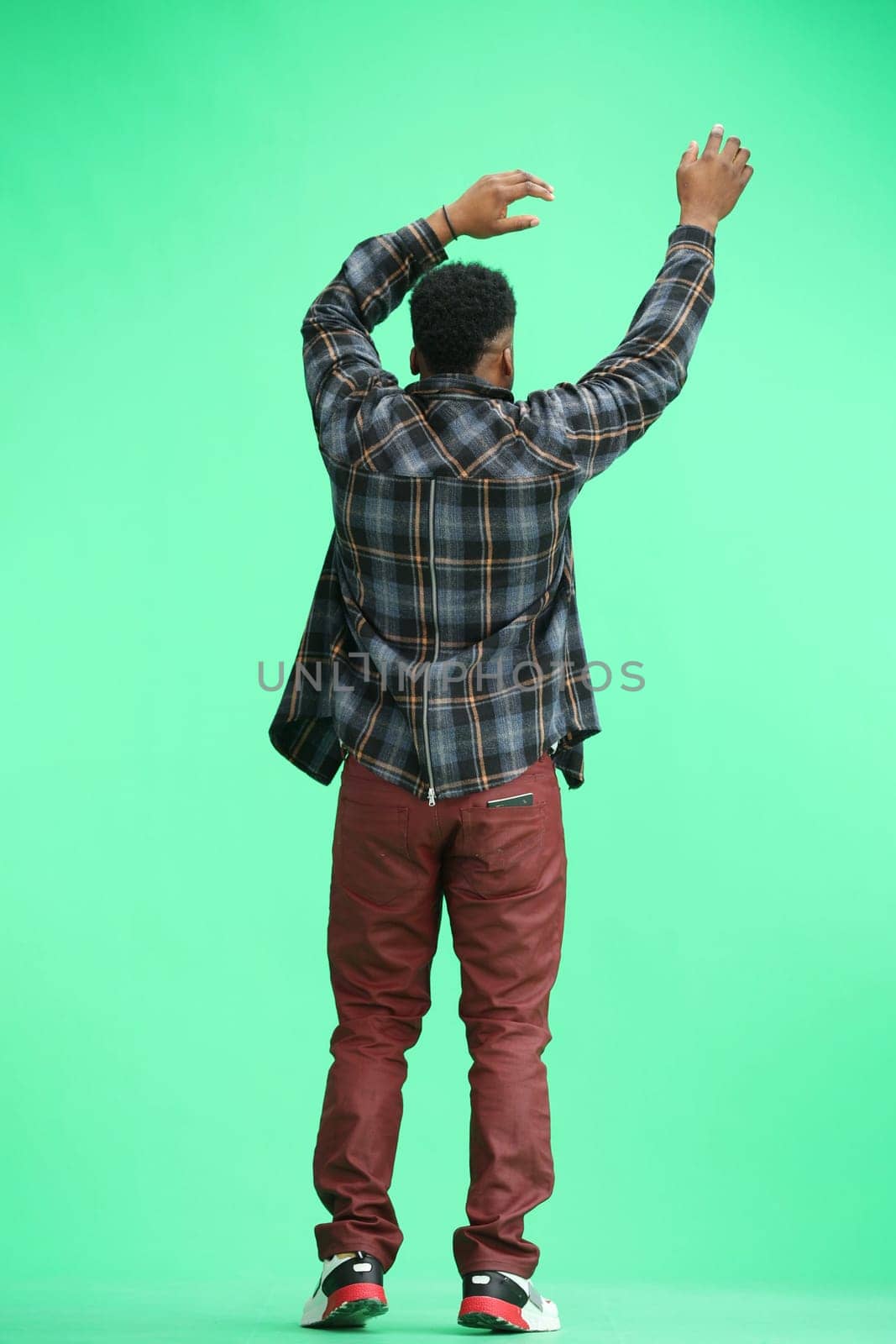 A man, full-length, on a green background, waving his arms.