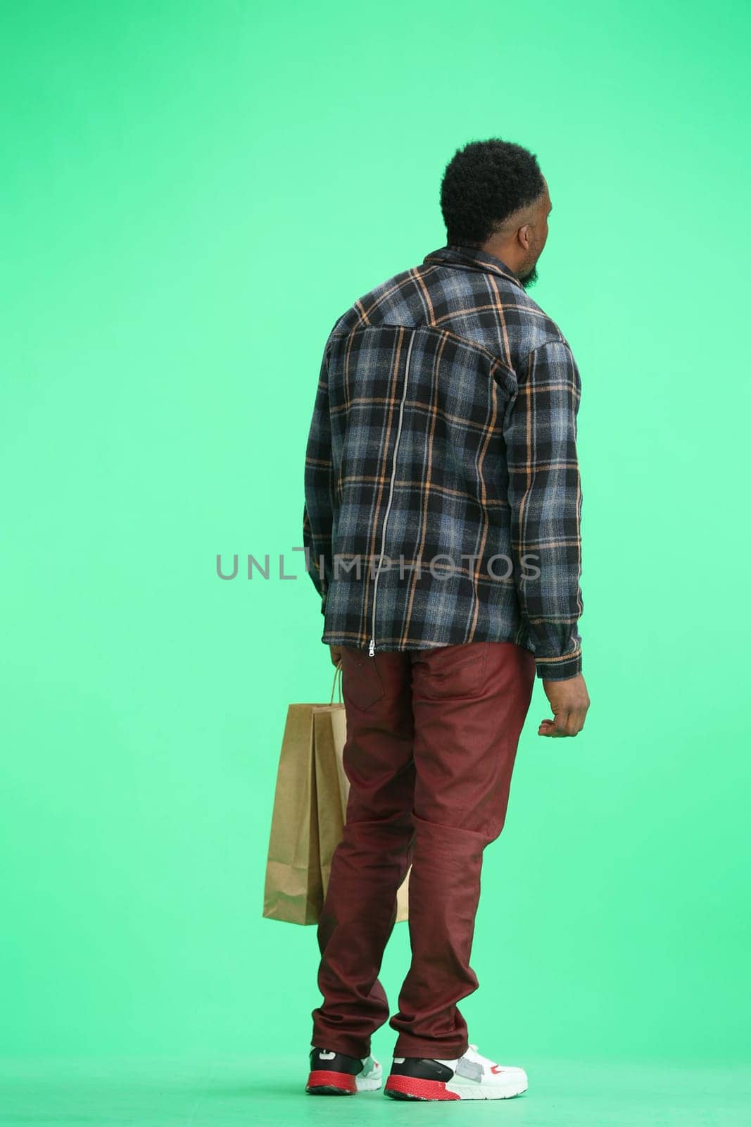 A man, full-length, on a green background, with bags by Prosto