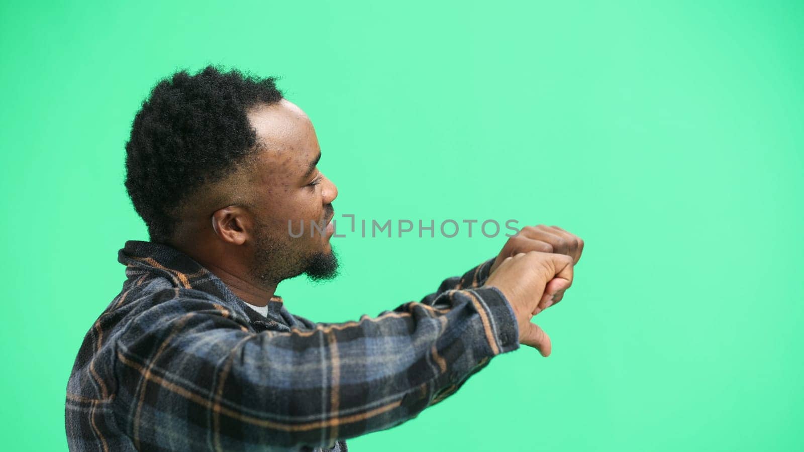 A man, close-up, on a green background, shows his thumbs down by Prosto