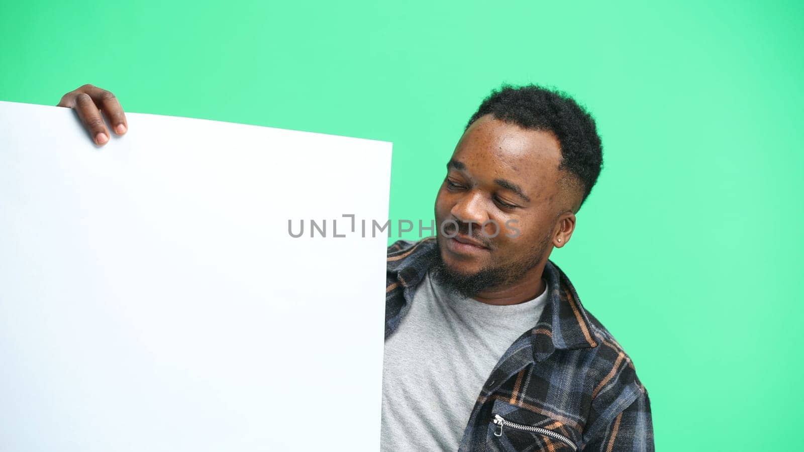 A man, close-up, on a green background, shows a white sheet by Prosto