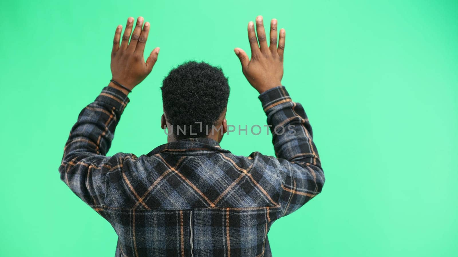 A man, close-up, on a green background, waving his arms.