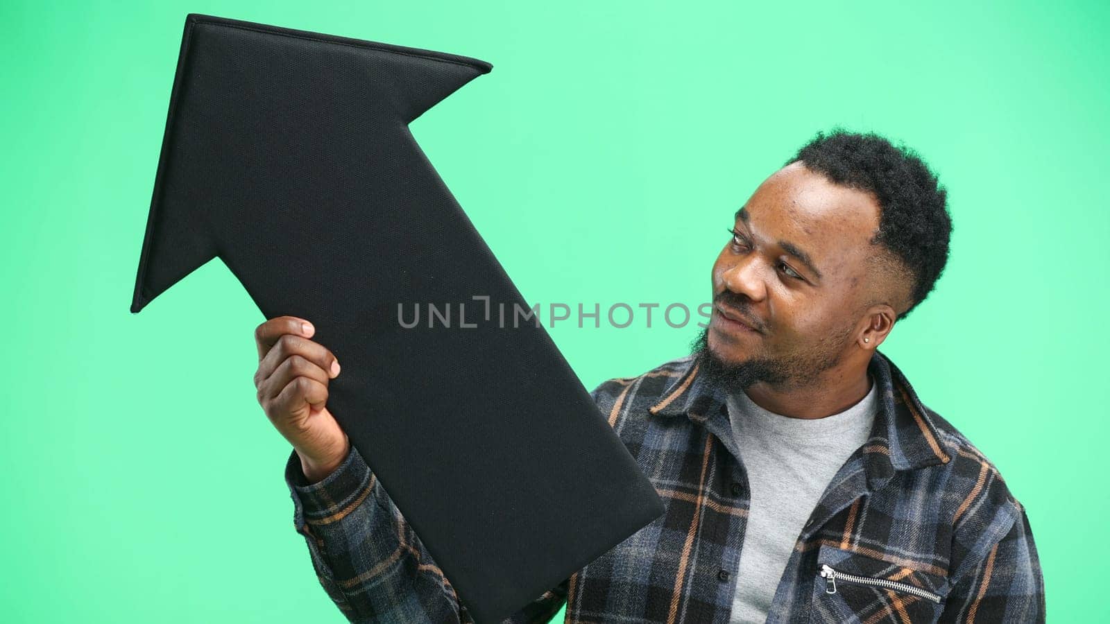 Man, close-up, on a green background, pointing up arrow.