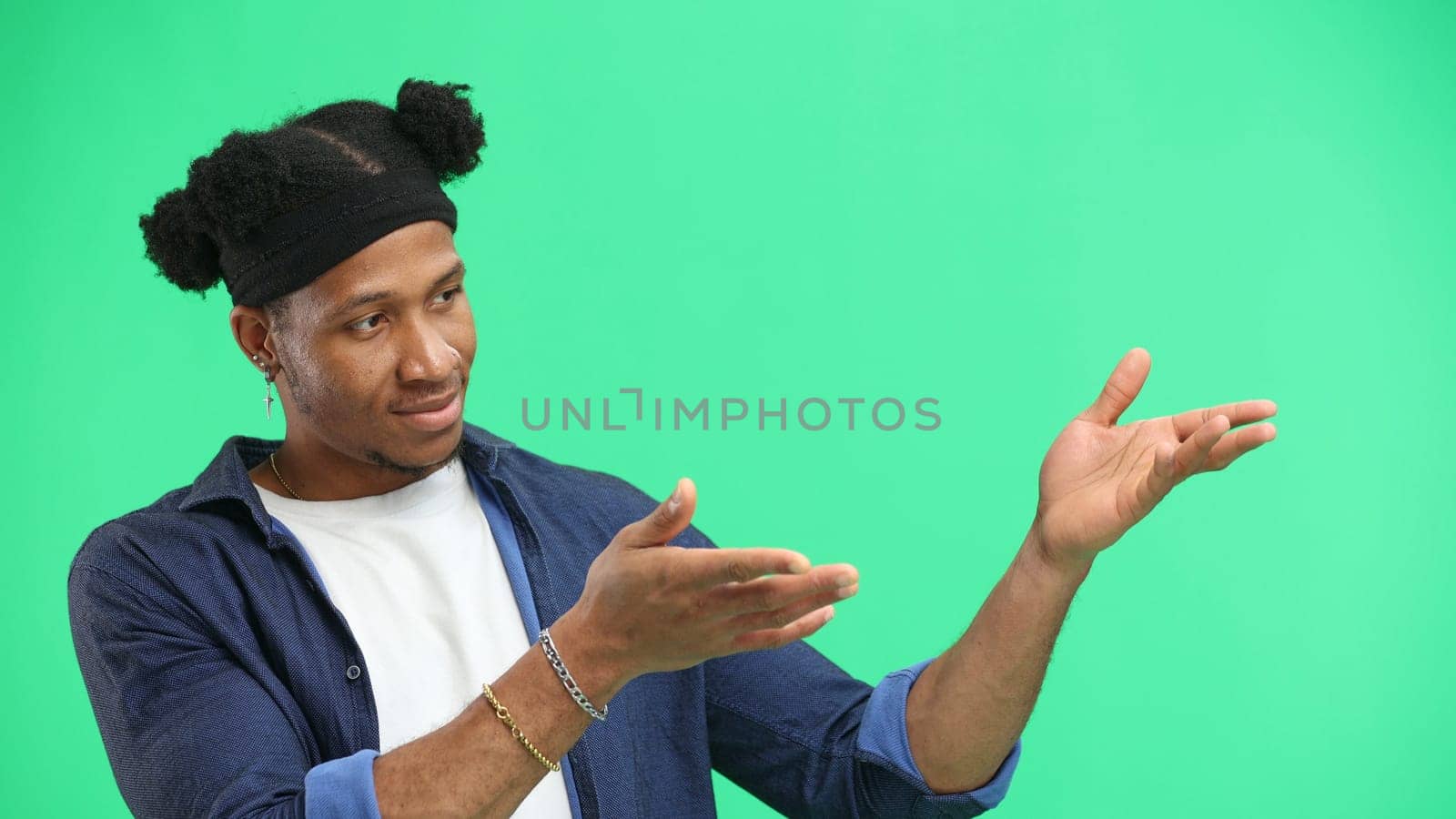 A man, close-up, on a green background, points to the side.