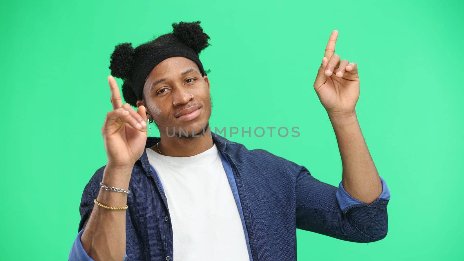 Man, close-up, on a green background, pointing up.