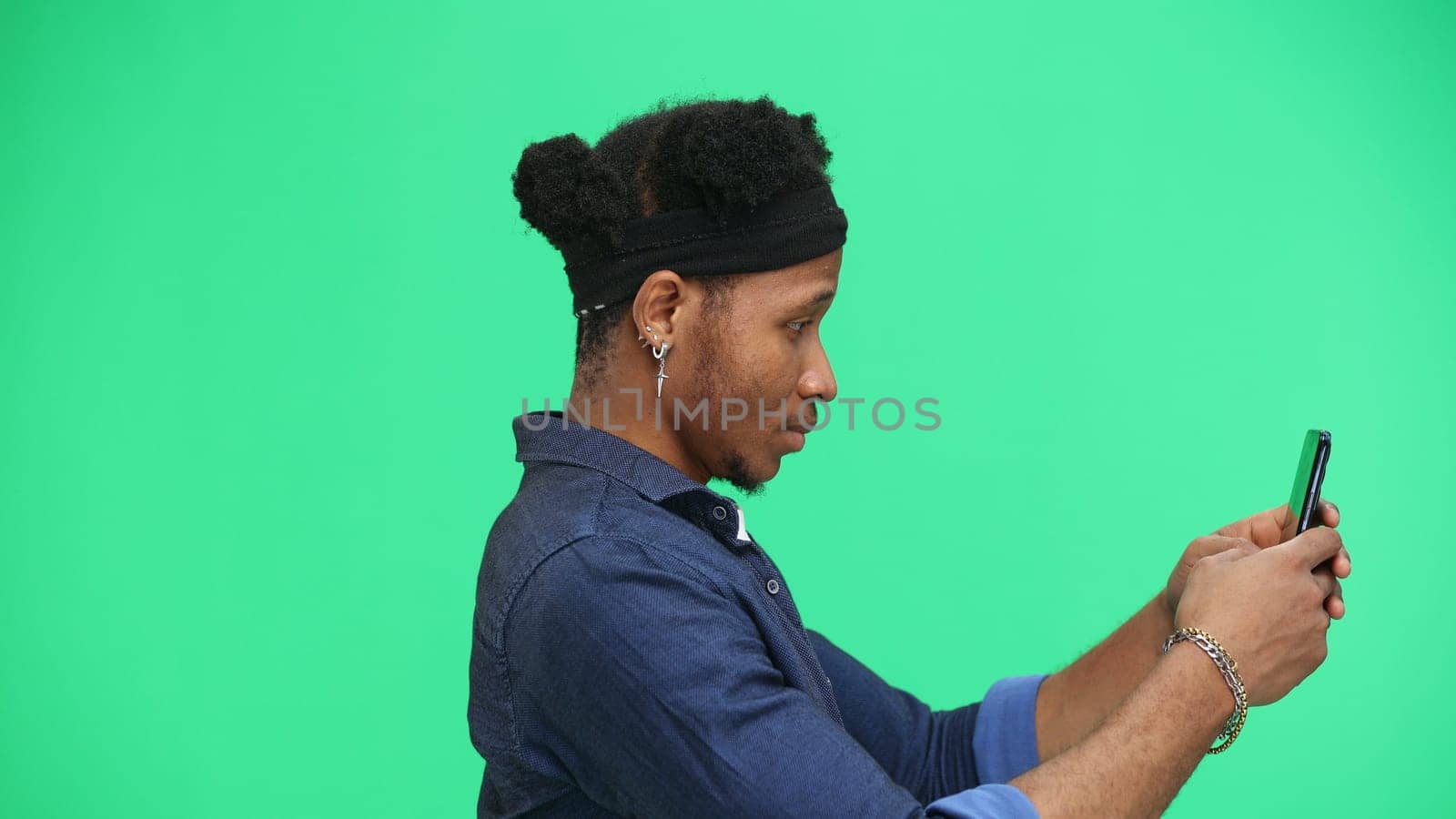 Man, close-up, on a green background, using a phone.