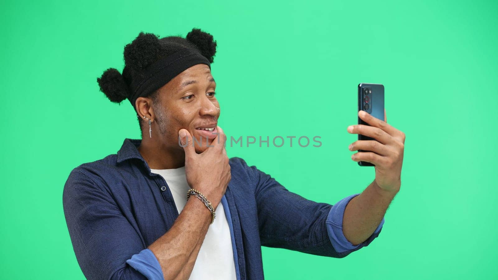 Man, close-up, on a green background, using a phone.