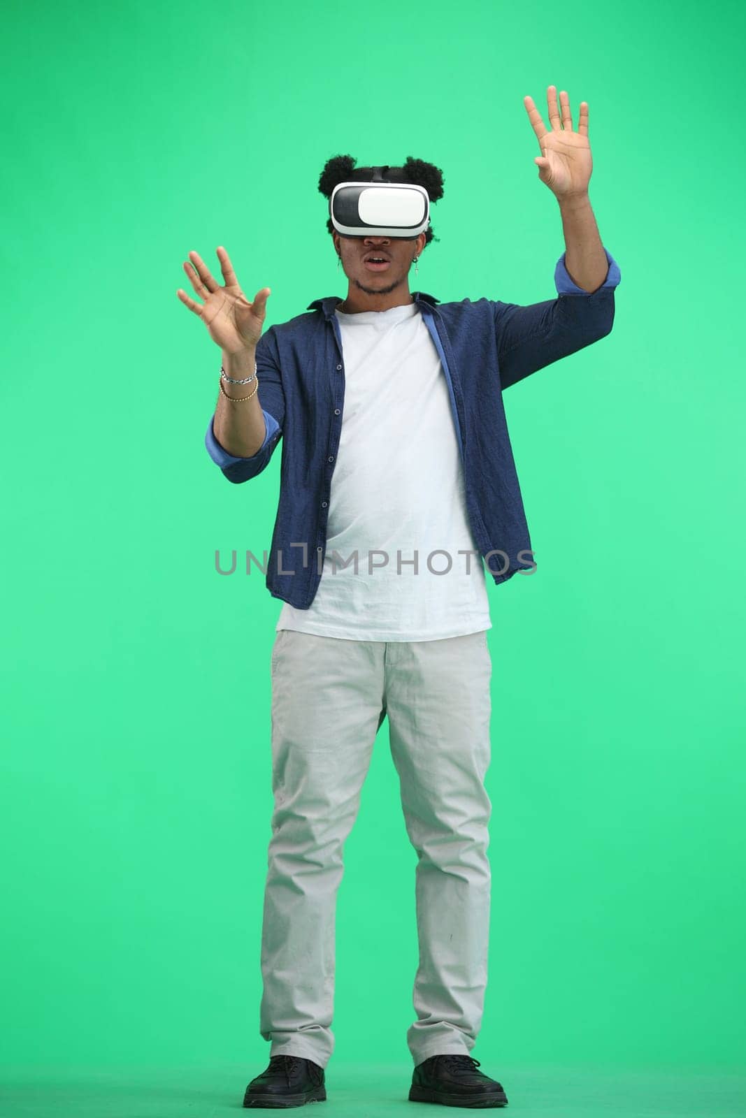 Man, full-length, on a green background, wearing VR glasses by Prosto