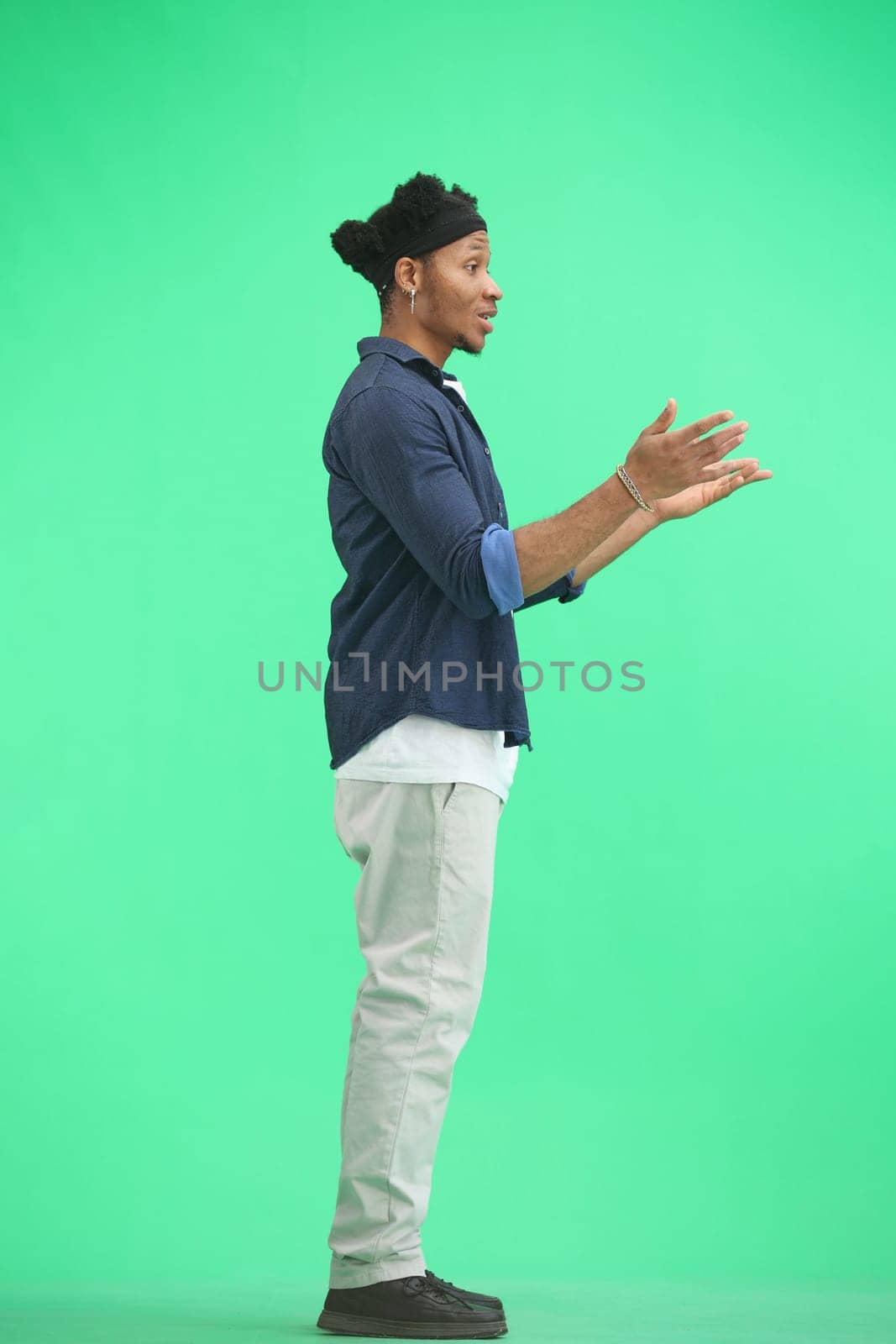 A man, full-length, on a green background, spreads his arms by Prosto