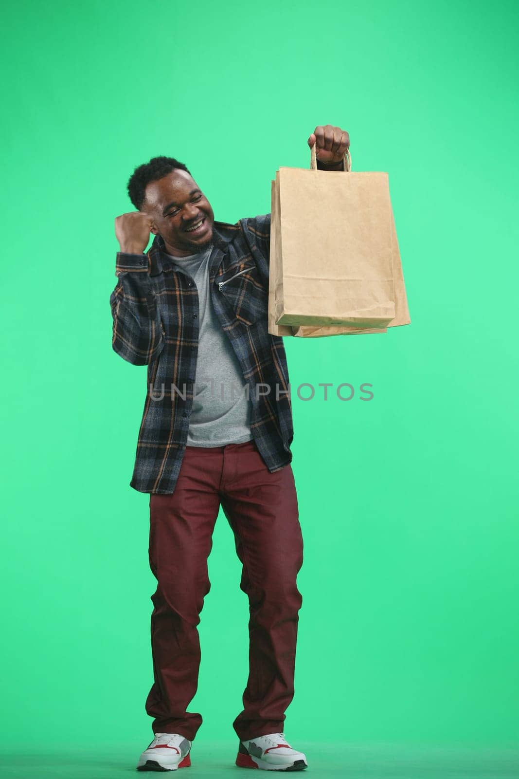 A man, full-length, on a green background, with bags by Prosto