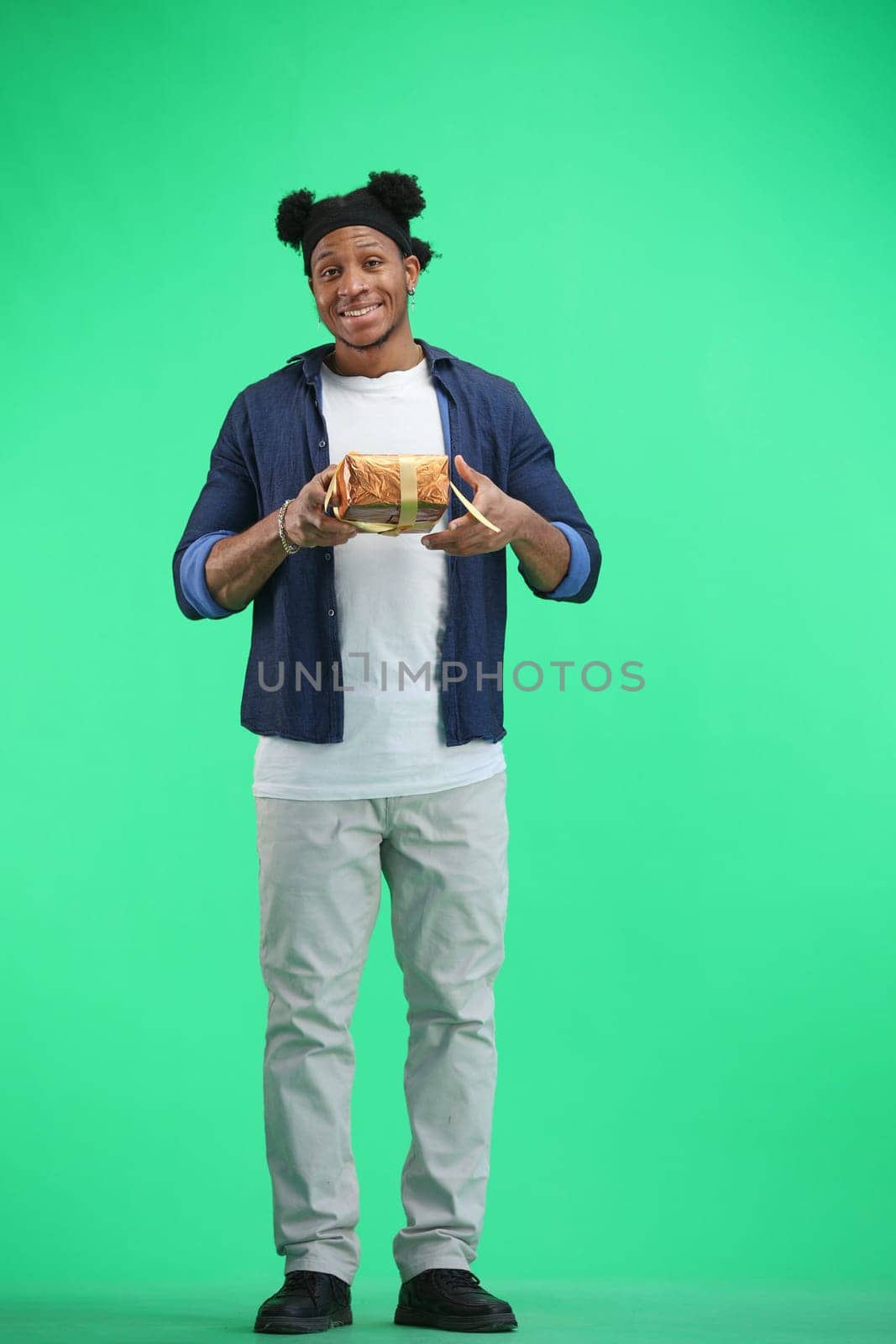 A man, full-length, on a green background, with a gift by Prosto