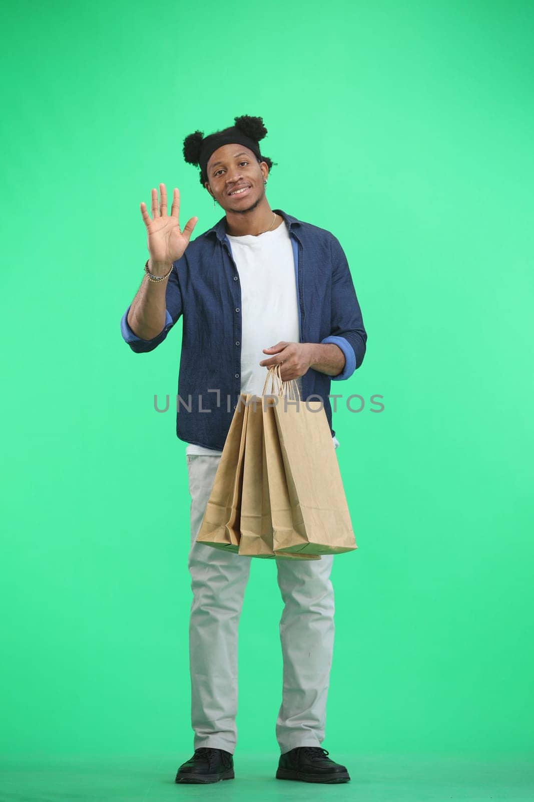 A man, full-length, on a green background, with bags, waving his hand by Prosto