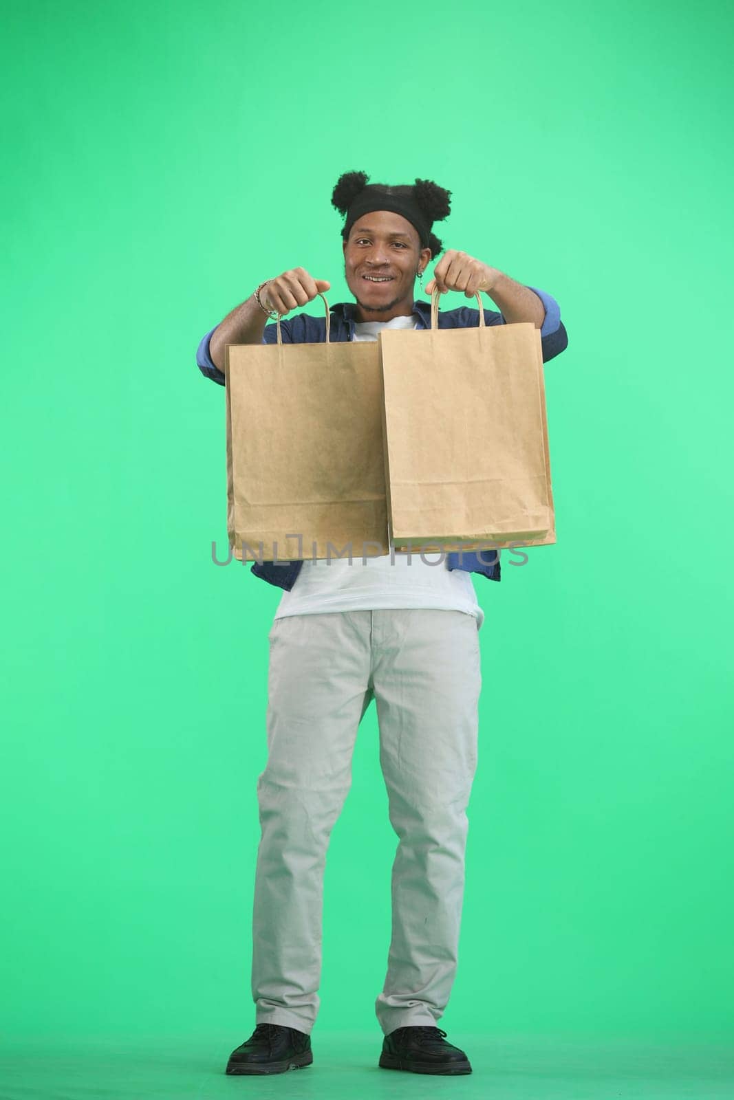 A man, full-length, on a green background, with bags by Prosto