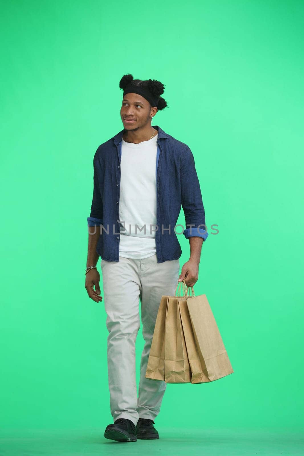 A man, full-length, on a green background, with bags by Prosto