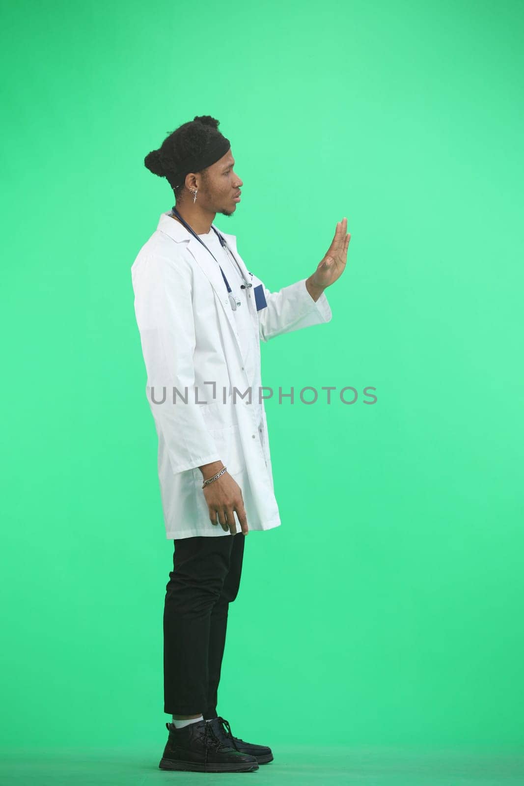 The doctor, in full height, on a green background, shows a stop sign.