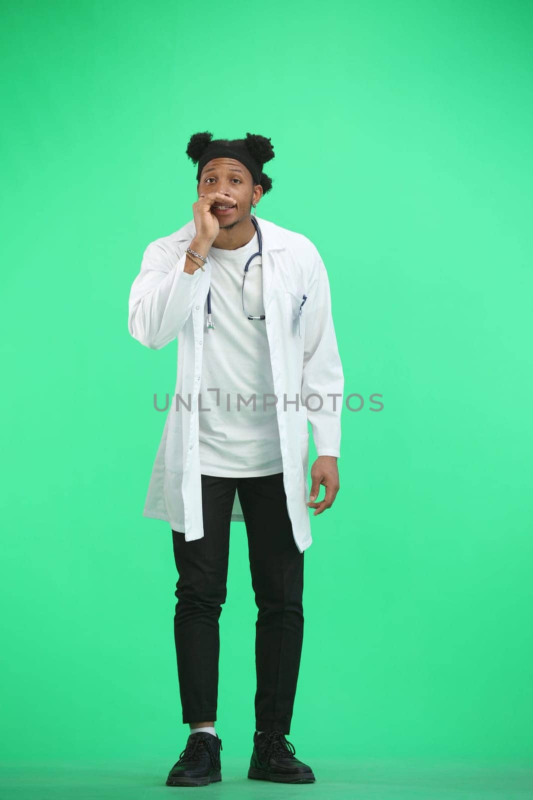 The doctor, in full height, on a green background, tells a secret by Prosto
