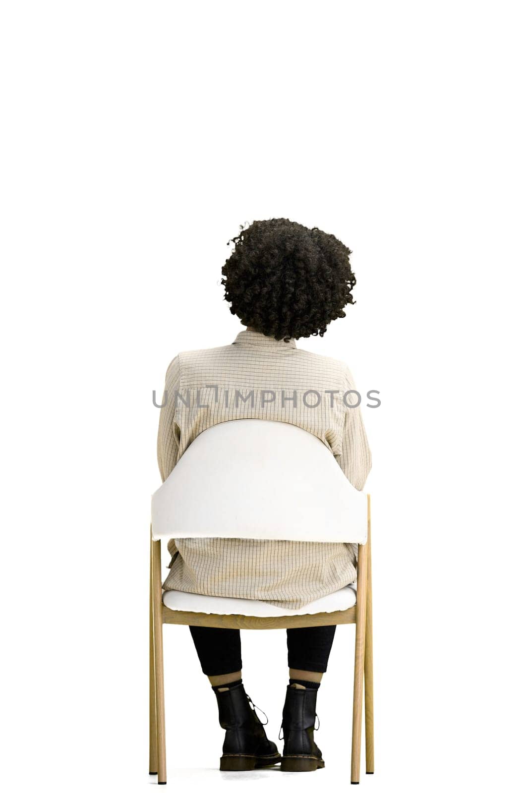 A woman, full-length, on a white background, sitting on a chair.