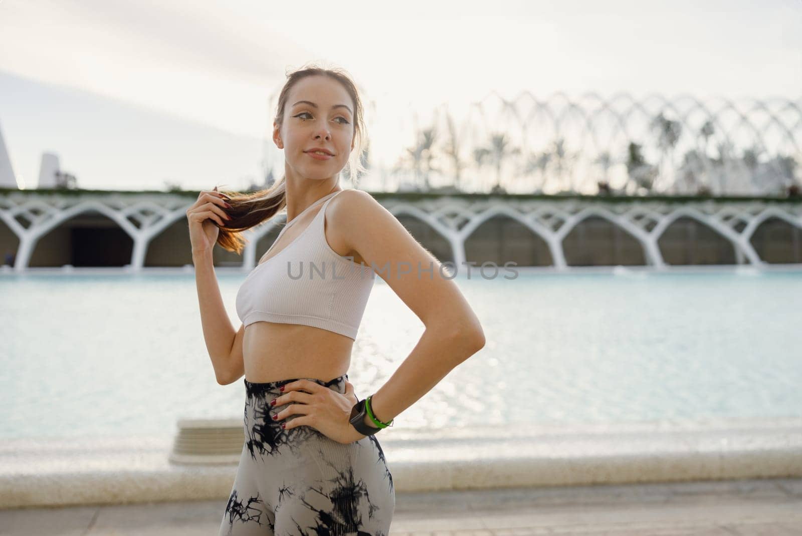 Pretty woman in sportswear have a rest after workout outside standing on building background by Yaroslav_astakhov