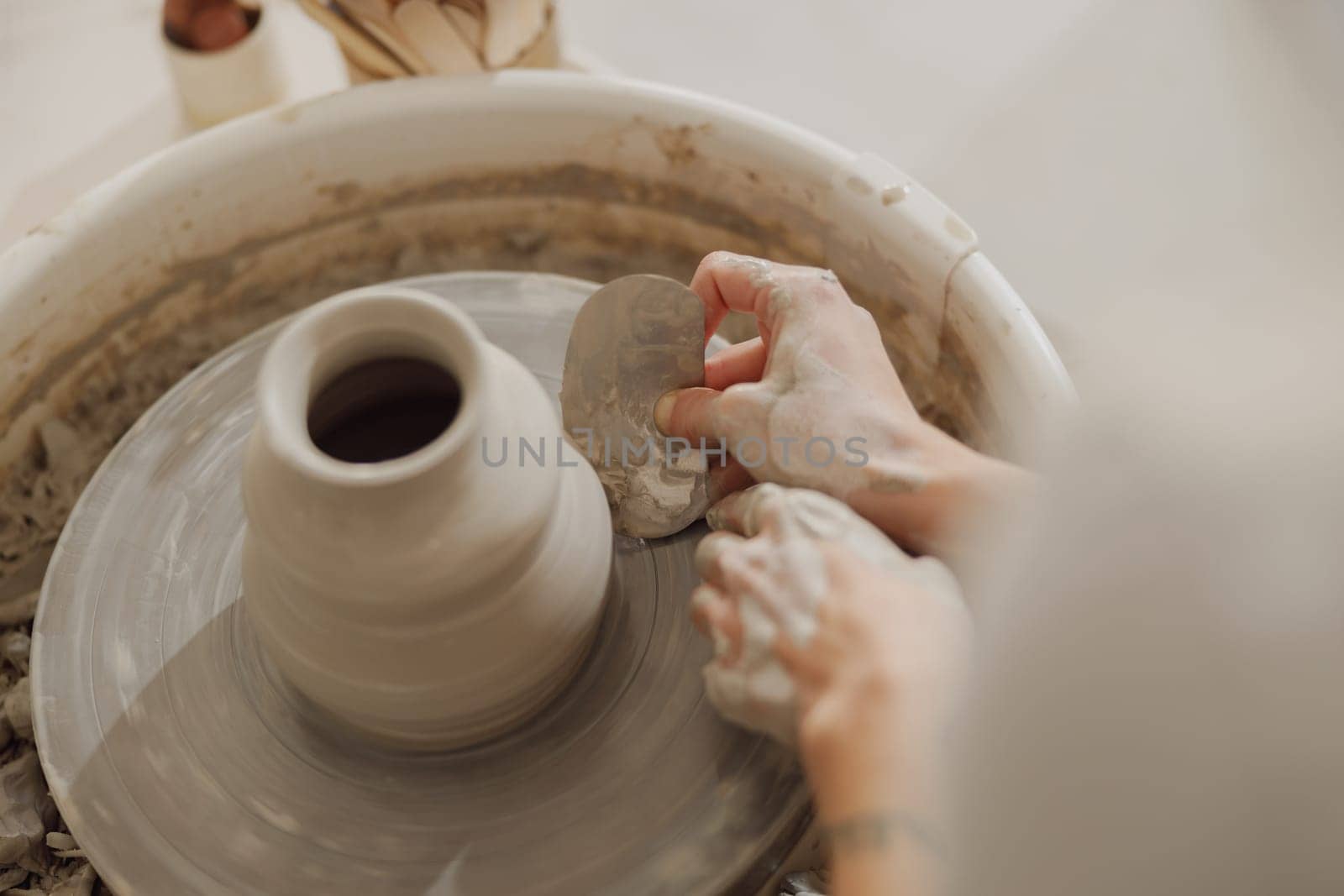 Close up of hands of professional potter molding pot shape on pottery wheel. Ceramics art concept by Yaroslav_astakhov