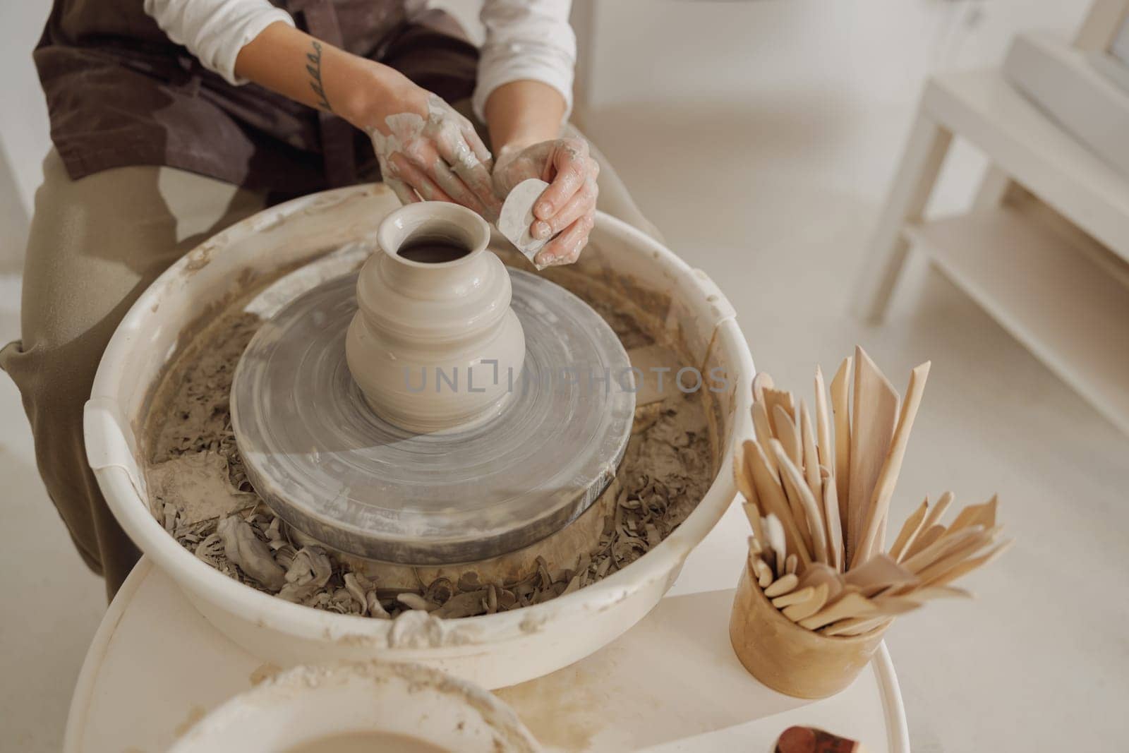 Close up of artisan's hands shaping clay bowl in pottery studio. Pottery art and creativity by Yaroslav_astakhov