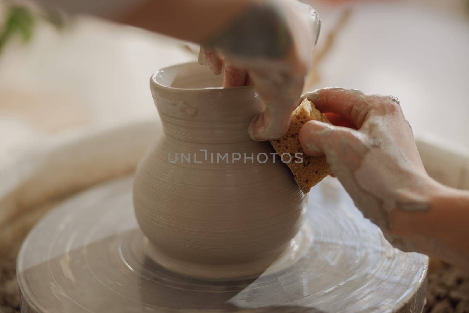 Close up of artisan's hands shaping clay bowl in pottery studio. Pottery art and creativity