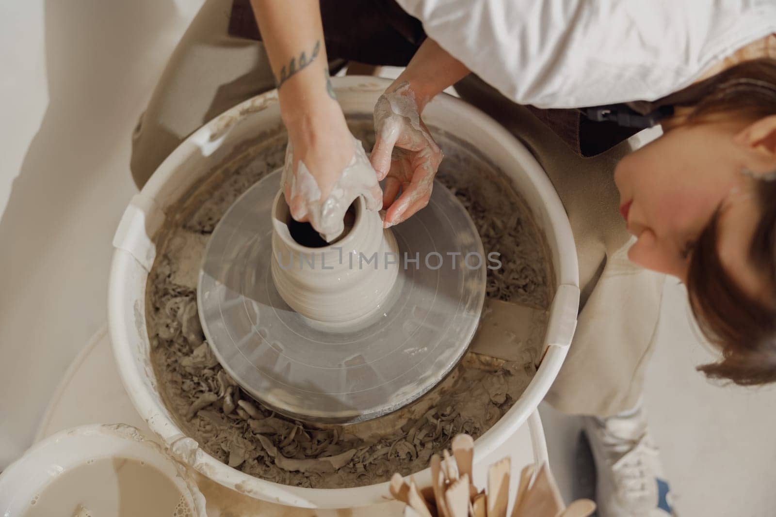 Close up of artisan's hands shaping clay bowl in pottery studio. Pottery art and creativity by Yaroslav_astakhov