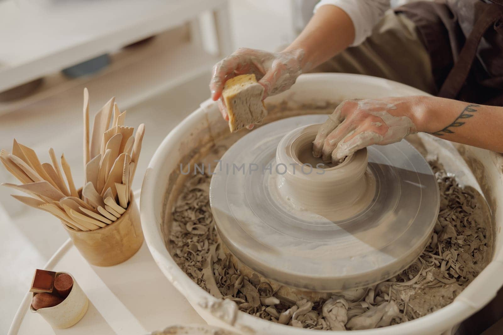 Close up of hands of professional potter molding pot shape on pottery wheel. Ceramics art concept by Yaroslav_astakhov