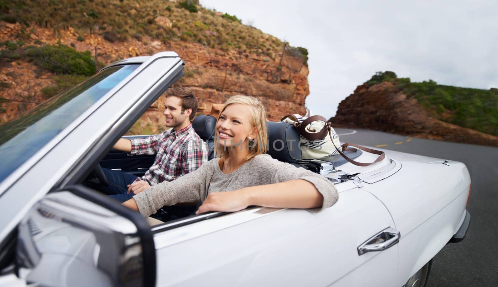 Happy couple, car and driving on road trip for travel, holiday weekend or outdoor vacation on street in nature. Young man and woman with smile for transportation or getaway in convertible vehicle by YuriArcurs