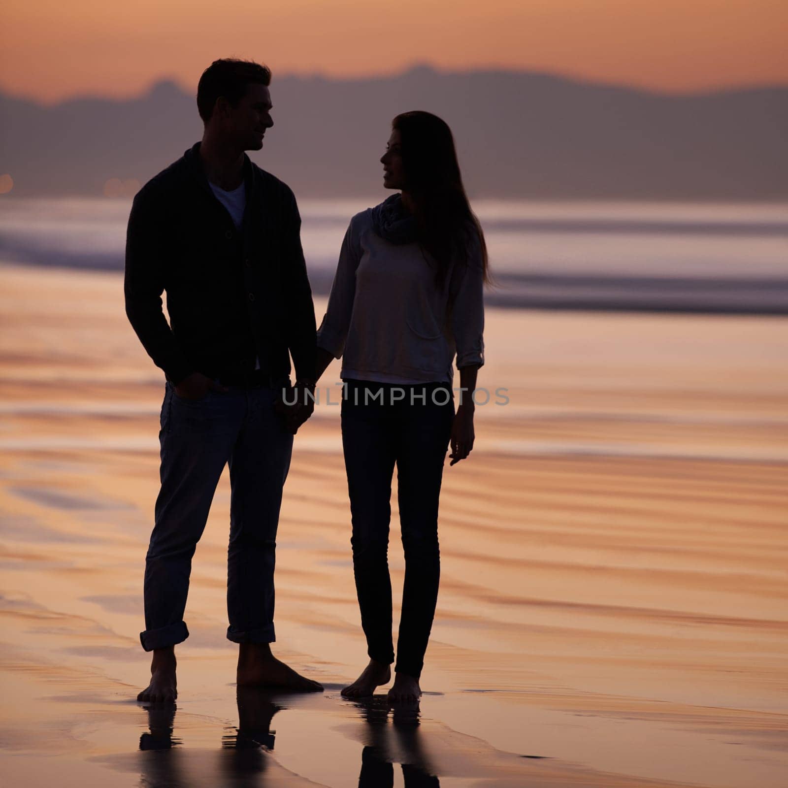 Couple, holding hands on beach and sunset, nature and travel with bonding for love and commitment outdoor. People with support, trust and loyalty with adventure together for honeymoon or anniversary.