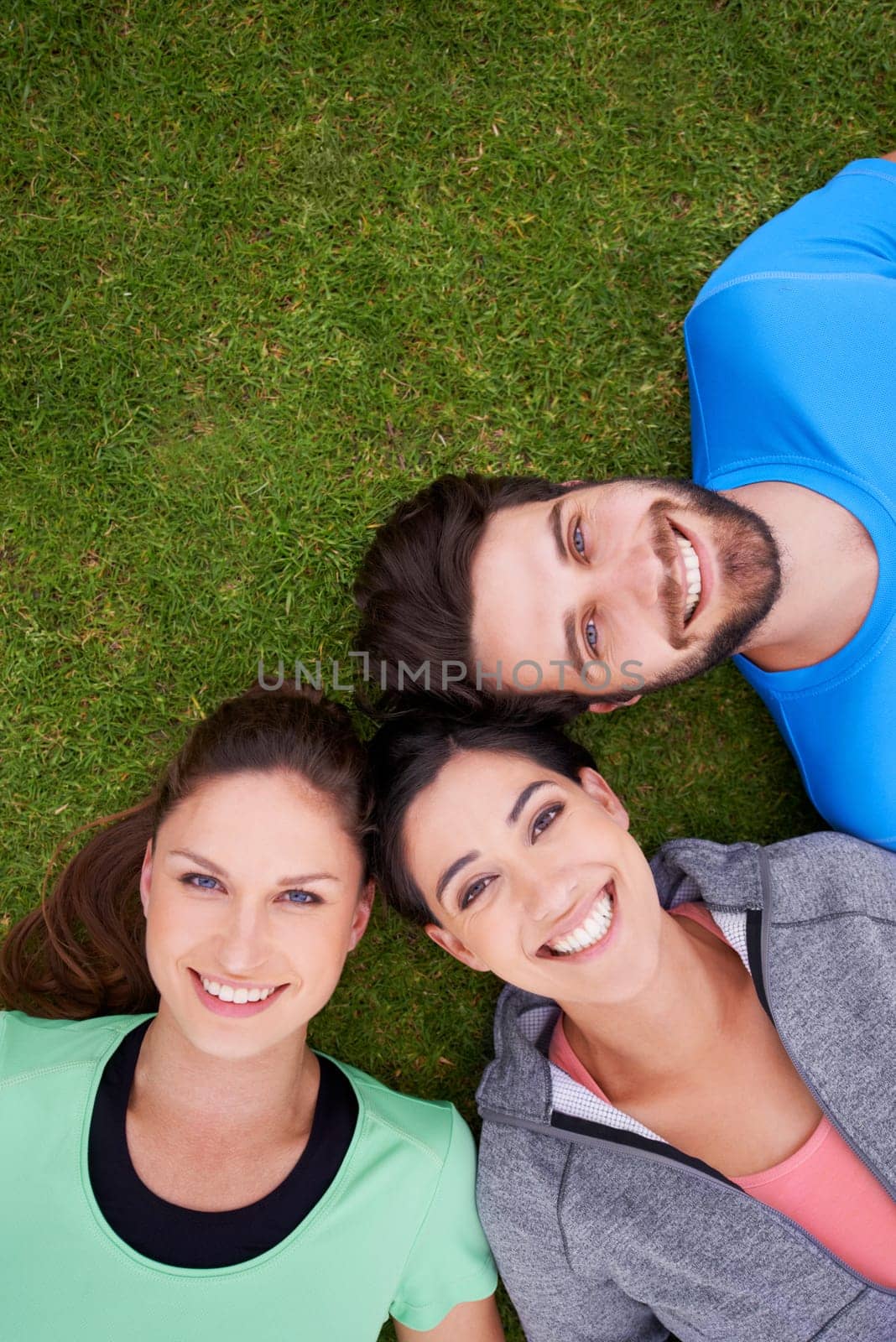 Smile, fitness and portrait of friends on grass for workout, exercise and healthy lifestyle from high angle. Sports, face and happy people outdoors for bonding, connection or break for training by YuriArcurs