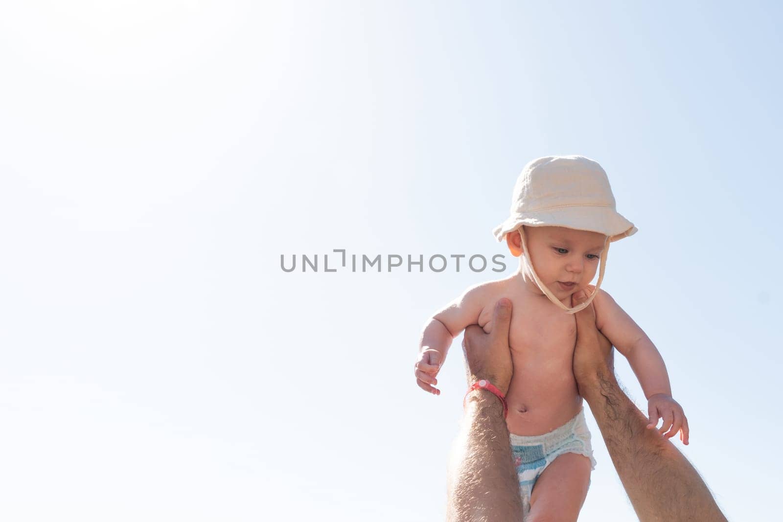 A magical moment under the sun as a father lifts his child, their bond shining as bright as the sunlight. Concept of carefree days and guiding love