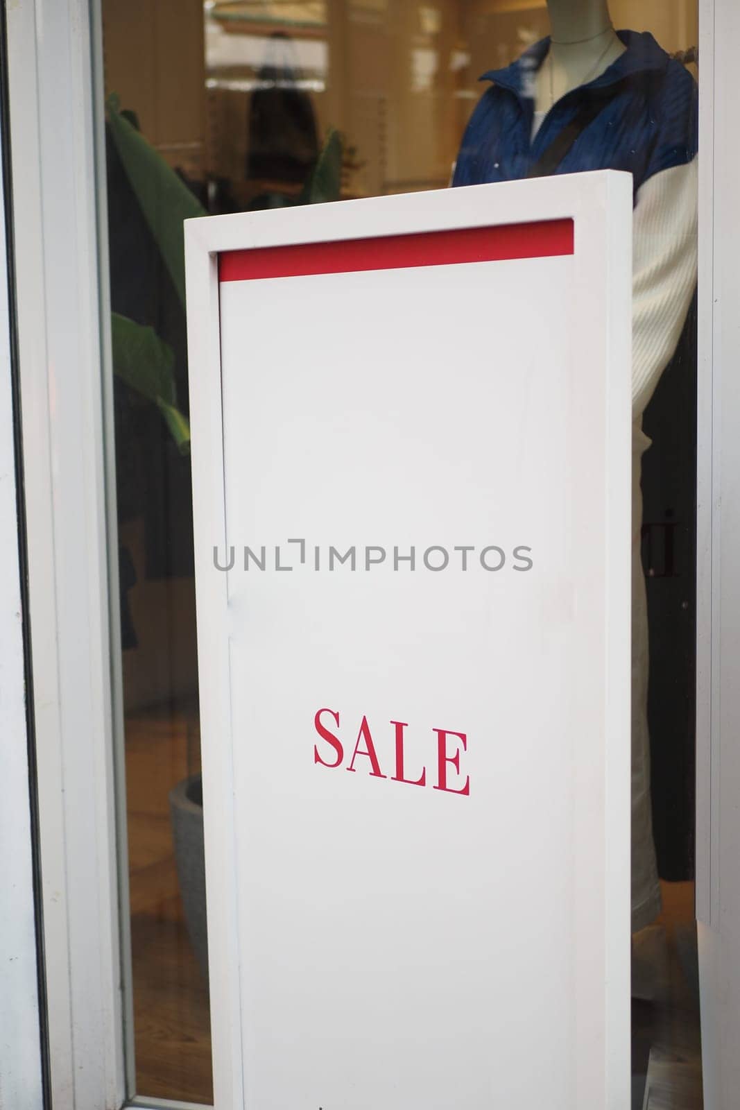 Large red Sale text letters on a glass wall obstruct a view inside the popular fashion store. High quality photo