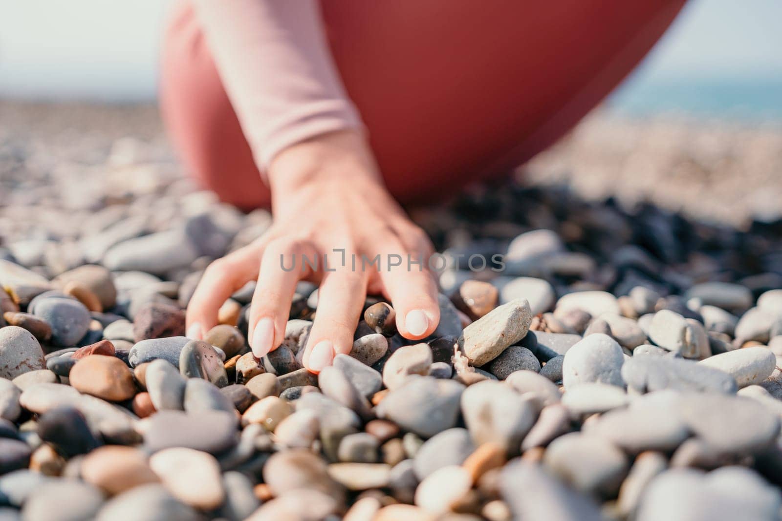 Middle aged well looking woman with black hair, fitness instructor in leggings and tops doing stretching and pilates on yoga mat near the sea. Female fitness yoga routine concept. Healthy lifestyle by panophotograph