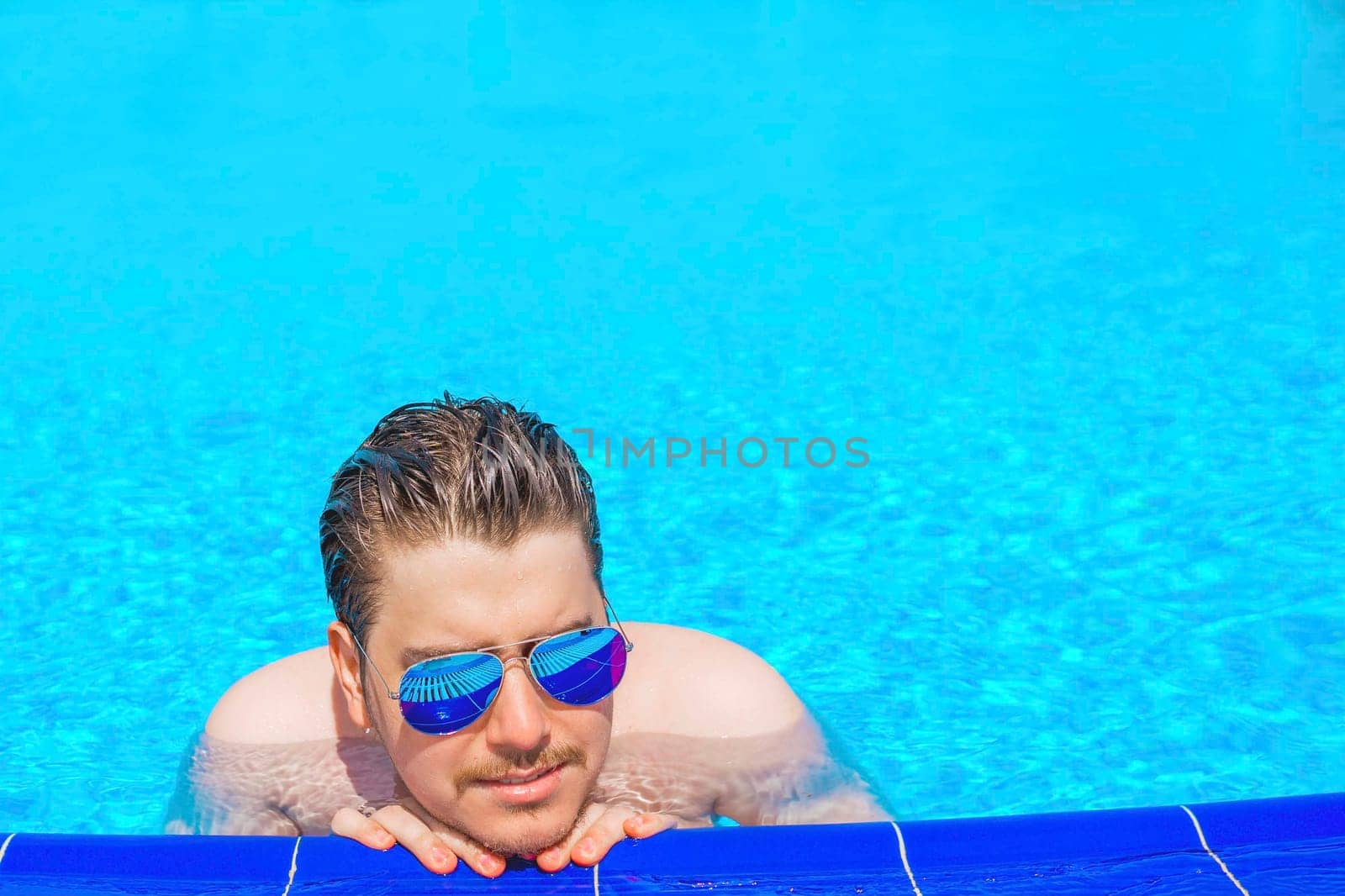 Man swimming in the pool. Man in pool having fun on summer holidays. Young man swimming and lurking on vacation.
