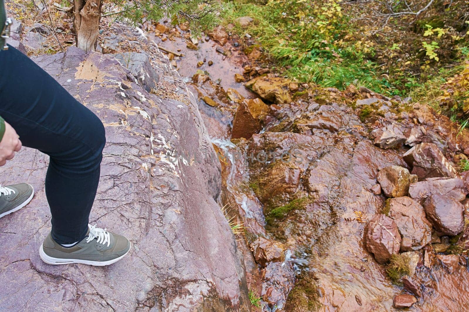 Female hiker walking in mountains forest. The woman found a beautiful stream in the mountains in the forest.
