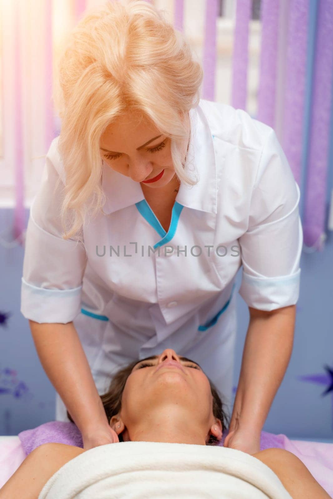 Masseur woman massages her shoulders. Woman getting a massage at the spa by Matiunina