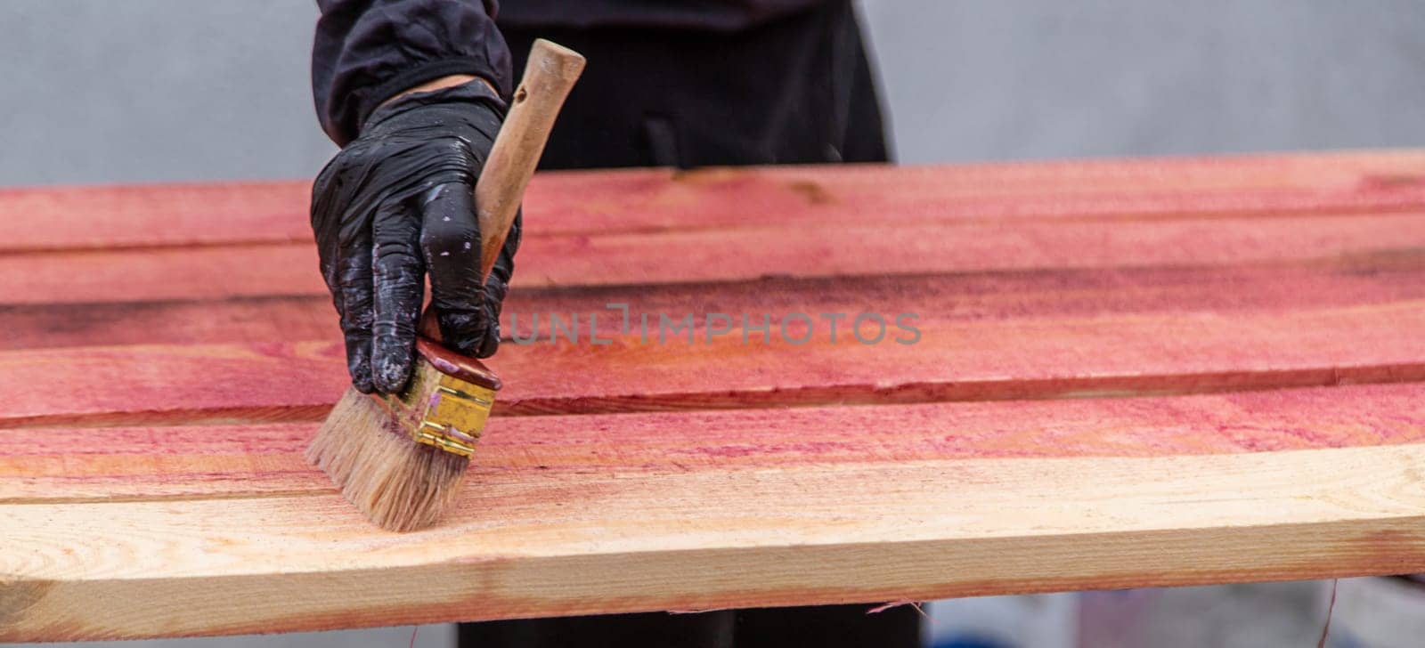 A man treats a board with a red antiseptic. selective focus. by yanadjana