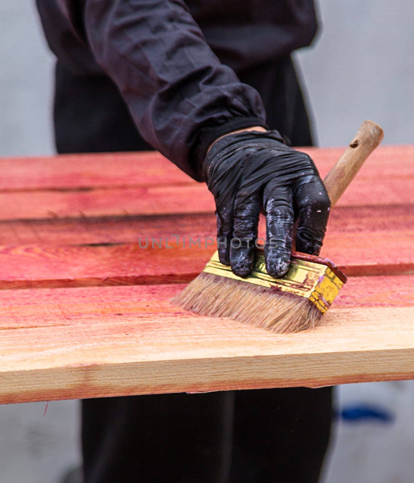A man treats a board with a red antiseptic. selective focus. Nature.